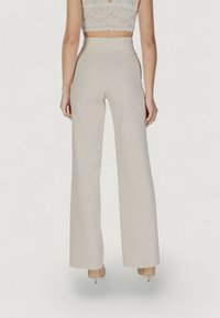 Pantaloni beige a vita alta e gamba larga realizzati in un tessuto liscio, caratterizzati da linee pulite e senza motivi visibili. L'orlo arriva a metà piede.
