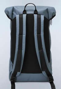 Mochila tipo roll-top con una tela texturizada gris, parte trasera de malla negra y correas ajustables negras. Cuenta con un asa en la parte superior para facilitar el transporte.