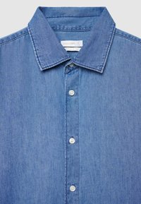 Hellblaues Denimhemd mit klassischem Kragen, Regular Fit und weißen Kunststoffknöpfen vorne. Die Textur wirkt weich.