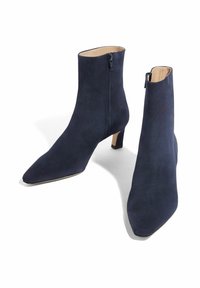 Tamno plave antilop čizme do gležnja s šiljastim nosom, unutarnjim patentnim zatvaračem i kratkom blok petom. Glatka tekstura s minimalističkim dizajnom.