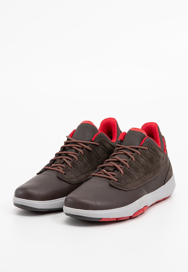 Braune Leder- und Wildledersneaker mit roten Akzenten, strukturierten Schnürsenkeln und einer weißen Mittelsohle. Sie verfügen über ein modernes Design und eine strapazierfähige Verarbeitung.
