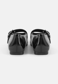 Sapatos pretos de cuique com bico arredondado, correia no tornozelo e um pequeno detalhe de fivela. textura suave com um salto baixo.