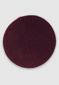 Berretto a maglia bordeaux con un motivo a coste testurizzate, forma circolare e un dettaglio centrale a stella. Materiale in lana morbida.