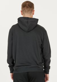Mörkgrå hoodie med k änguruficka, ribbade ärmslut och resårsnodd i huvan. Tyget verkar mjukt med en slät textur.