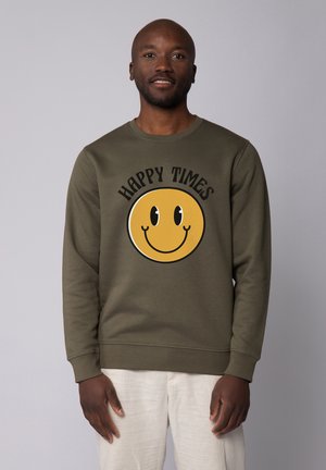 Olijfgroene sweatshirt met een rond gele smiley-gezicht grafiek, zwarte tekst met "HAPPY TIMES," en ribgebreide manchetten en zoom. Zachte textuur.