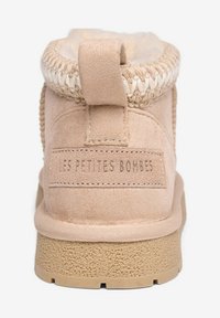Botte chelsea en suède beige avec semelle texturée, bord tressé en haut et une boucle à l'arrière pour un enfilage facile. Logo "LES PETITES BOMBES" sur le talon.