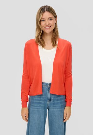 Cardigan corallo a maniche lunghe con apertura frontale, polsini a costine e vestibilità comoda, sovrapposto a una maglietta bianca, abbinato a jeans blu a vita alta.