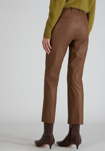 Bruine leren broek met een slim fit en enkel lengte. Kenmerkt zich door achterzakken, een soepele textuur en een strakke uitstraling. Gepaard met bruine haklaarzen.