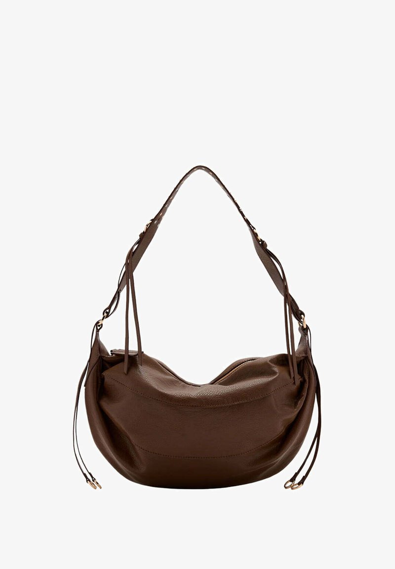 Sac à bandoulière en cuir marron avec une forme incurvée, une bandoulière réglable et des pompons en cuir décoratifs de chaque côté.
