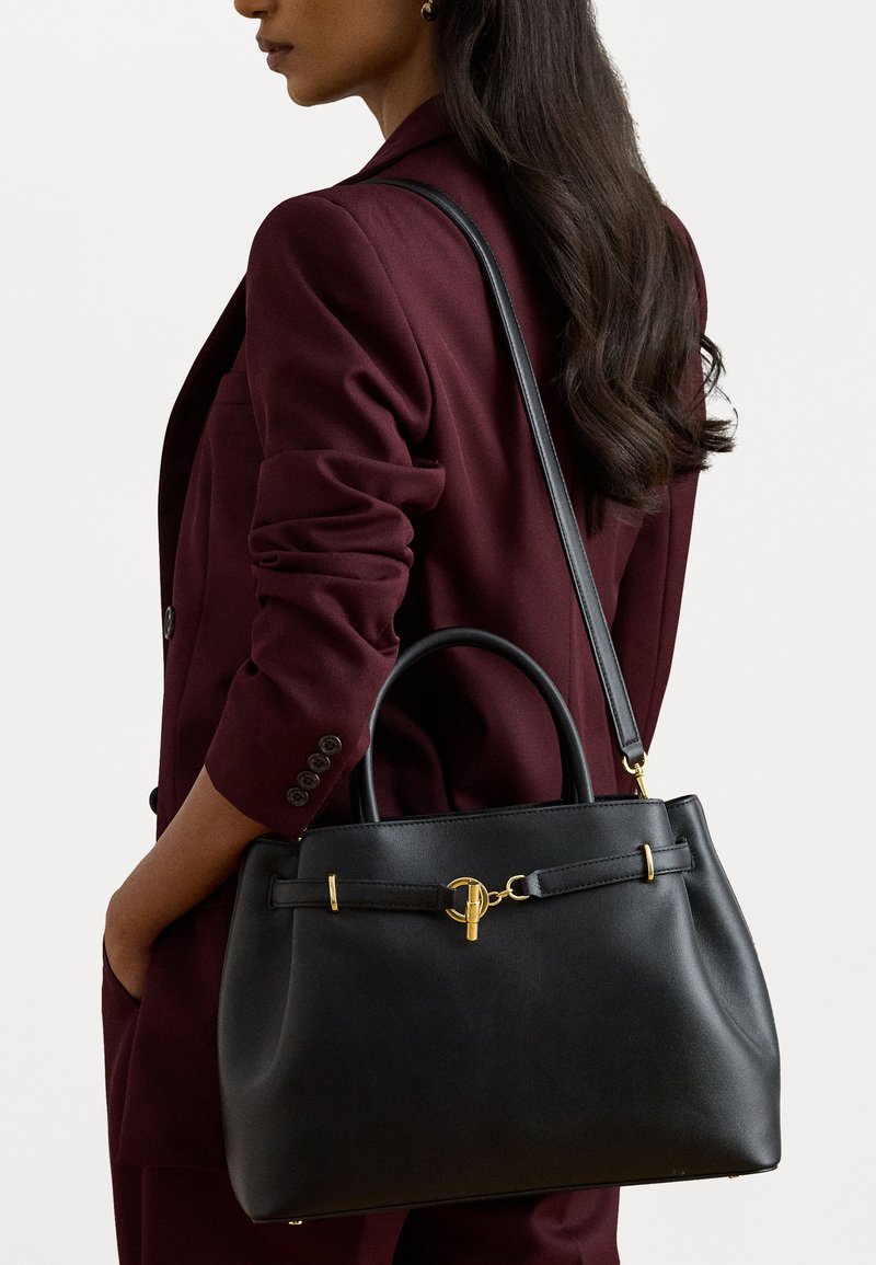 Čierna kožená kabelka so zlatým kovovým hardware, štruktúrovaný tvar, dvojité uši a odnímateľný ramenný popruh.