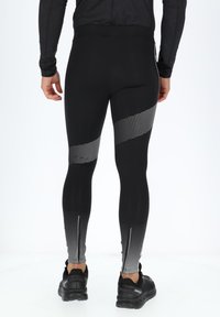 Zwarte sportleggings met een geometrisch zilveren stippenpatroon aan de zijkanten, met een hoge tailleband en ritsen bij de enkels.
