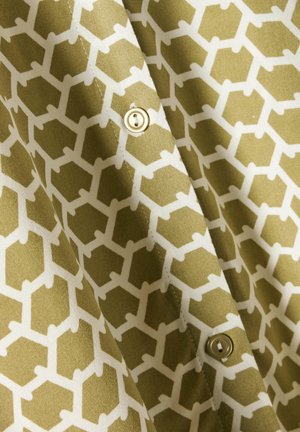 Tela verde oliva con un patrón geométrico blanco que presenta hexágonos y líneas, acentuado por un detalle de botón dorado.