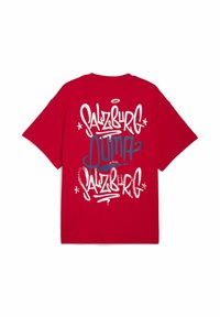 Rød kortærmet t-shirt med hvid og navy graffiti-stil tekst, der læser "SALZBURG" og "OUMA" i et lagdelt design.