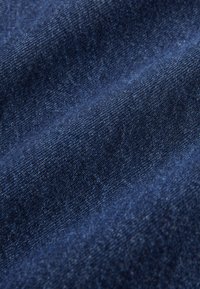 Tessuto denim blu scuro con motivo di tessitura diagonale, che mostra una trama fine e leggere pieghe nel materiale.