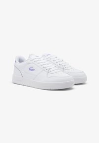 Białe skórzane sneakersy z sznurowadłami, perforowanym czubkiem oraz purpurowym logo na boku i pięcie. Smukły design z teksturowaną gumową podeszwą.