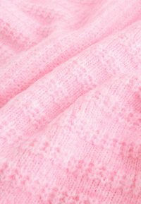 Light pink knitted fabric with a soft texture, featuring a subtle pattern and varying knit stitches throughout the surface.