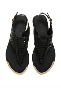 Black sandals with woven straps and a slingback design. Features a smooth, textured sole and a gold accent on the toe.