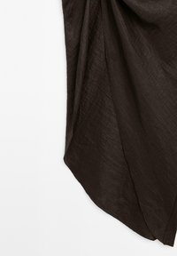 Mørkebrun stof med en struktureret, lidt krøllet overflade, der flyder ned fra det øverste venstre hjørne i en trekantet form.