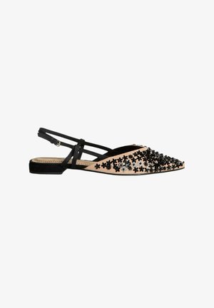 Zapato slingback negro y beige con punta afilada, adornos florales, tacón plano y correa ajustable. Presenta una parte superior de tela y acentos texturizados.