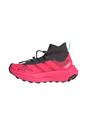 Czerwone i czarne buty do biegania w terenie Adidas Terrex Gore-Tex z wysokim kołnierzem wokół kostki i gumową podeszwą Continental, zaprojektowane do użytku na zewnątrz.
