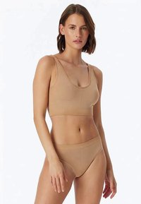 Beženi grudnjak i gaćice napravljeni su od mekog, rastezljivog materijala. Grudnjak ima bešavni dizajn i široke naramenice, dok gaćice imaju srednje visoki kroj.