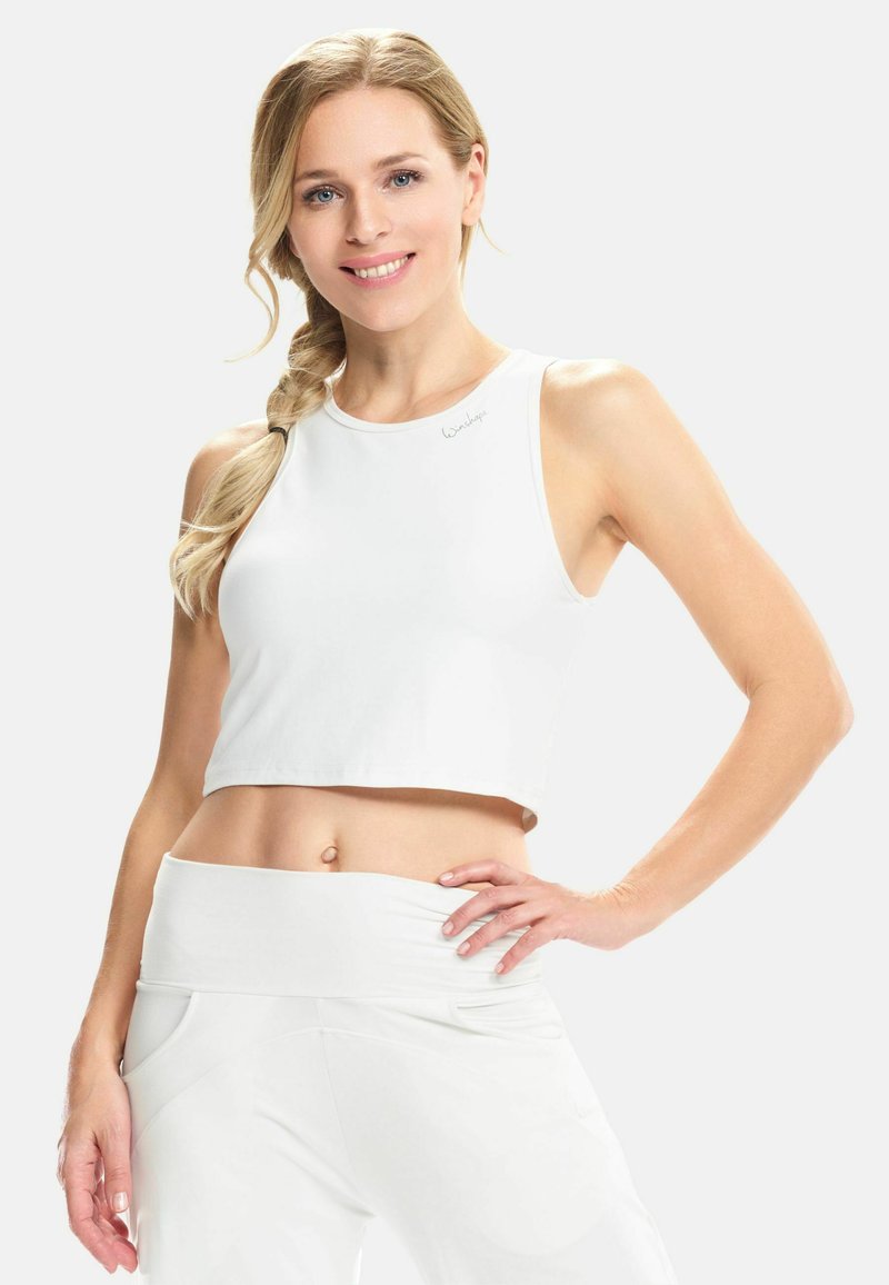 Top corto bianco realizzato in tessuto liscio, con scollatura alta e accento logo sulla spalla. Abbinato a pantaloni bianchi coordinati.