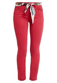 Pantalons en denim rouge avec une coupe skinny, dotés d'une ceinture en tissu à motifs nouée à la taille. Texture lisse avec des poches frontales standard.