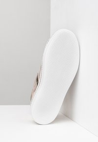 Sandalo con tomaia rosa testurizzata, suola in gomma bianca e dettagli metallici, caratterizzato da un design minimalista e stile slip-on.