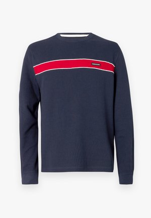 Tamsiai mėlyna ilgomis rankovėmis marškinėliai su ribotu raštu, su horizontalia raudona juosta ir baltomis detalėmis per krūtinę, su logotipo etiketėle.