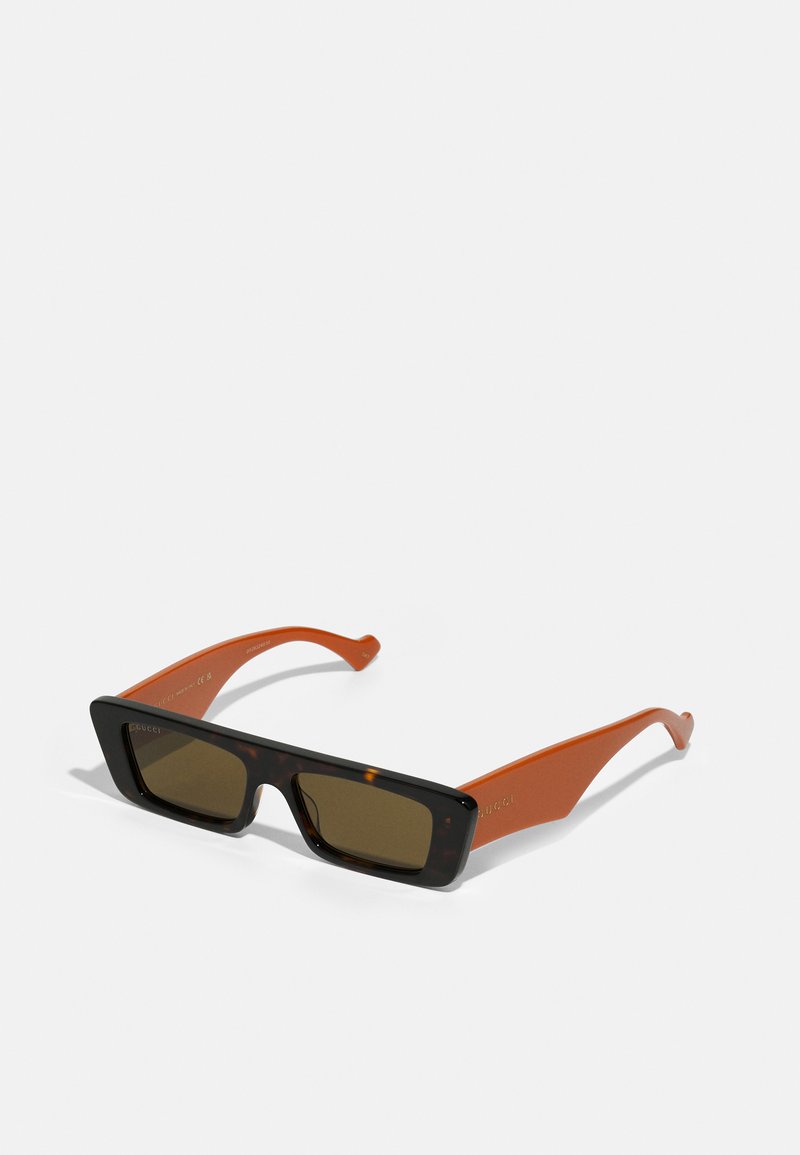 Occhiali da sole rettangolari con fronte in tartaruga e stanghette arancioni; dotati di lenti marroni. Stampe "Gucci" all'interno della stanghetta.