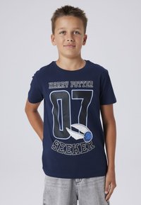 Camiseta de algodón azul marino con el gráfico "HARRY POTTER 07 SEEKER" que presenta un snitch de Quidditch y detalles de alas en blanco y azul claro.