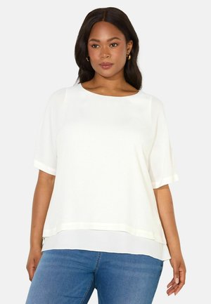 Haut blanc à manches courtes avec un col rond et un ourlet inférieur superposé. Texture lisse avec un léger éclat. Associe avec un jean en denim bleu.