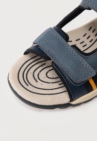 Sinised nahast sandaalid reguleeritavate rihmadega, tekstureeritud hall sisetald ringikujuliste mustritega ning kerge must kummine tallaosa.