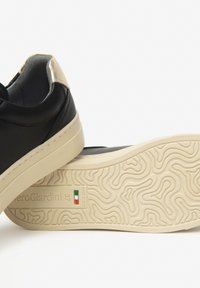 Schwarze Leder-Sneaker mit einem metallisch goldenen Fersenakzent. Cremefarbige Gummisohle mit strukturiertem Grip-Muster. Größe 37, hergestellt in Italien.
