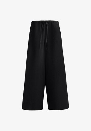 Pantaloni negri largi, cu craciii scurtați și talie elastică cu șnur frontal, realizați dintr-un material ușor.