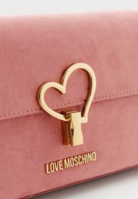 Borsa a pochette in suede rosa con chiusura in metallo a forma di cuore dorato e logo "LOVE MOSCHINO" impresso sulla parte anteriore. Design semplice ed elegante.