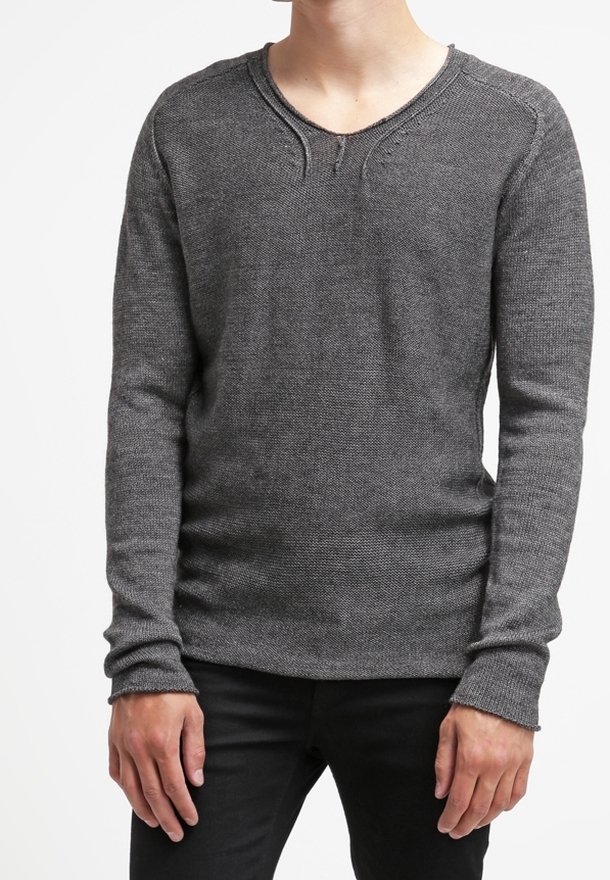 Homme portant un pull en maille ajusté, manches longues, gris foncé avec un col rond et un pantalon noir sur fond blanc.