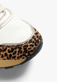 Zapatillas de leopardo con un material texturizado similar al terciopelo, acentos metálicos y una suela de goma negra, combinando elementos de diseño moderno.