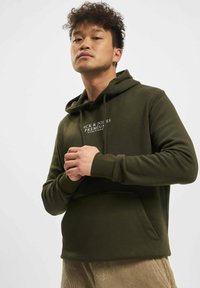 Olivengrønn hettegenser med framlomme, justerbar snorhette og hvit trykket merkevare på brystet. Glatt tekstur og uformell design.