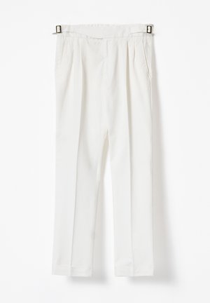 Pantalones blancos de cintura alta con pliegues delanteros, bolsillos laterales y hebillas laterales ajustables, colgados contra un fondo blanco.