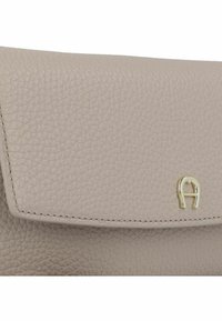 Hellbeige Leder-Clutch mit strukturierter Oberfläche; verfügt über ein goldfarbenes Metalllogo und eine Naht entlang der Kanten.
