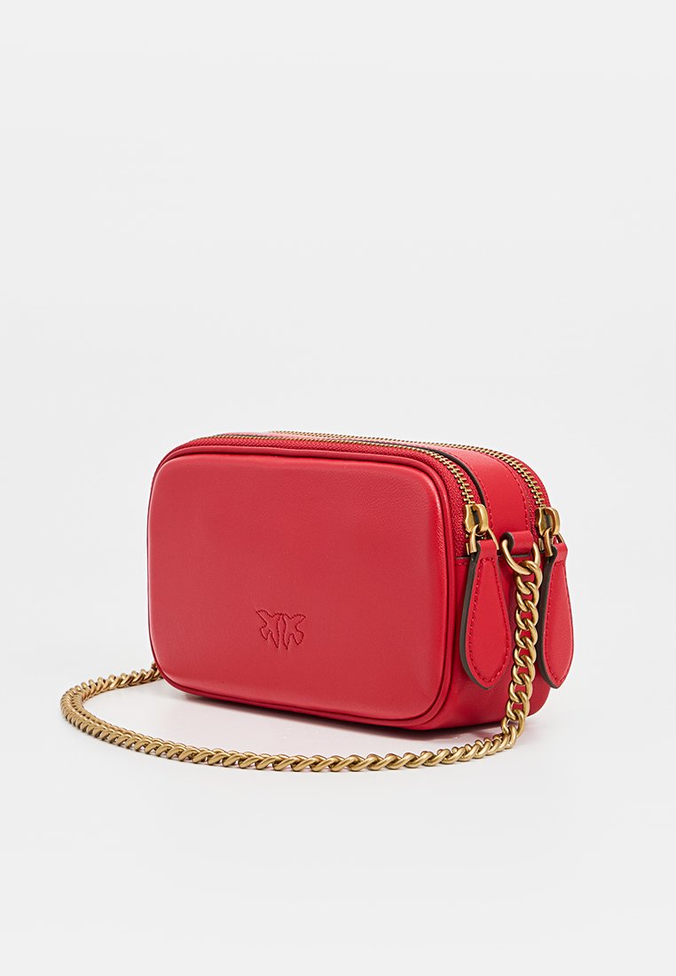 Sac bandoulière en cuir rouge avec fermeture zippée, bandoulière en chaîne dorée et détail de logo embossé. Forme rectangulaire avec texture lisse.
