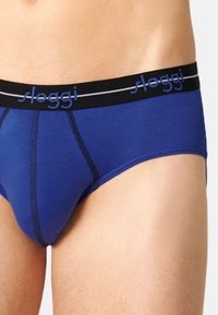 Blaue Slip-Unterwäsche mit einem schwarzen Bund, der mit dem "sloggi"-Logo versehen ist, kontrastierenden Nähten und einem enganliegenden Design.