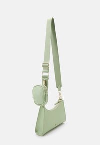 Sac bandoulière vert clair avec sangle réglable et pochette ovale petite attachée, les deux avec des zips et des détails de quincaillerie dorée.