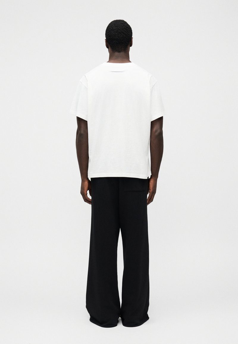 Hvid bomuld T-shirt med rund hals, kombineret med løse sorte bukser. Enkel design, afslappet pasform og uden synlige mønstre eller hardware.