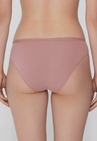 Světle růžové bavlněné bikiny s hladkým povrchem, středním pasem a minimálními švy. Jednoduchý design s plným pokrytím.