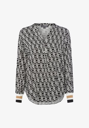 Blusa a maniche lunghe bianco e nero con motivo geometrico, colletto a doppia apertura e polsini a costine con strisce bianche, beige e nere.