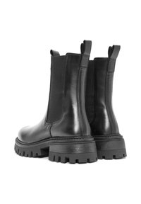 Botas de cuero negro con paneles laterales elásticos, lengüetas de tracción, suela de goma negra gruesa y bordes texturizados en la suela para mayor agarre.