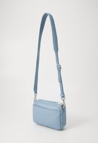 Borsa a tracolla in pelle blu chiaro con finitura texturizzata, scomparti con zip e tracolla regolabile. Design rettangolare minimalista.