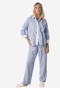 Niebiesko-białe paskowane piżamy z luźną koszulą na guziki i dopasowanymi spodniami z elastycznym paskiem w talii oraz swobodnym krojem.